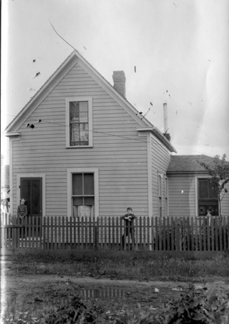 Print from large post card negative.  Girl on far left looks like it may be Laura Randell. Other girl could be Raye Jones and boy could be George Jones.
House number is 108. Location unknown.